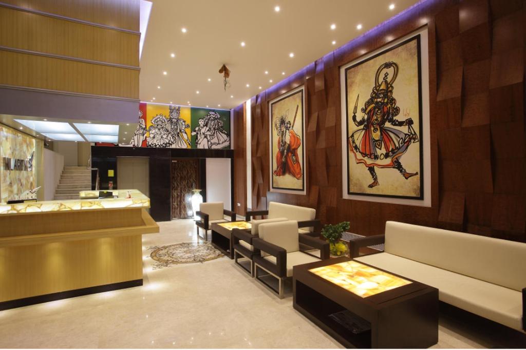 a lobby with couches and paintings on the walls at Hilarity Inn in Padappai