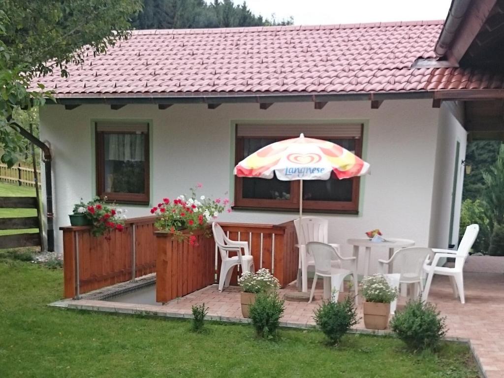 une petite maison avec une table et un parasol dans l'établissement Cosy holiday home with sauna in the Allg u, à Burggen