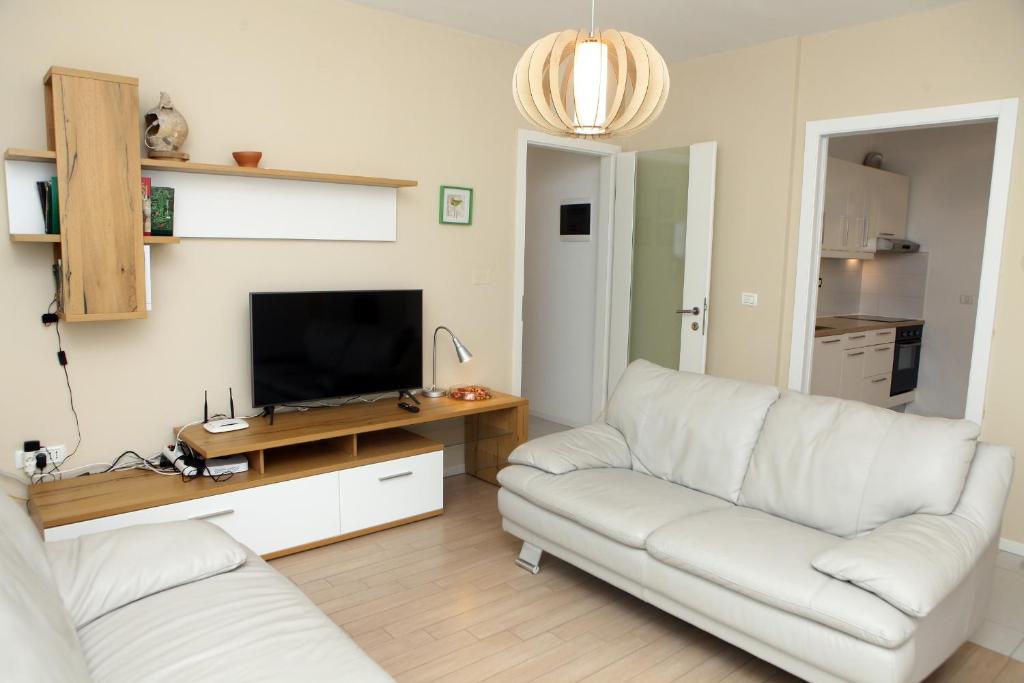 un salon avec deux canapés blancs et une télévision dans l'établissement Koper Homey Retreat LURE, à Koper