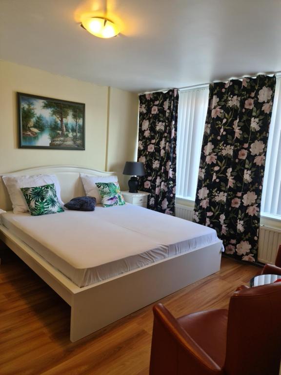 Un dormitorio con una gran cama blanca con dos ventanas. en Tamar 2, en Katwijk aan Zee