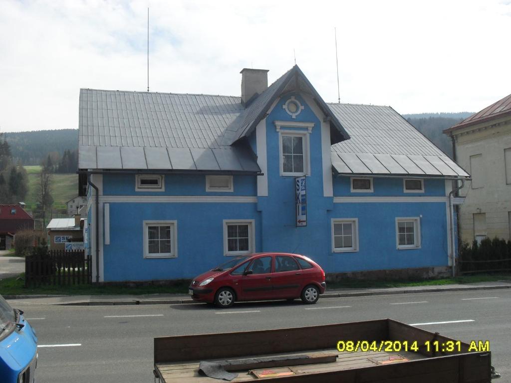 una casa azul con un coche rojo estacionado frente a ella en Modrý Dům, en Horní Maršov