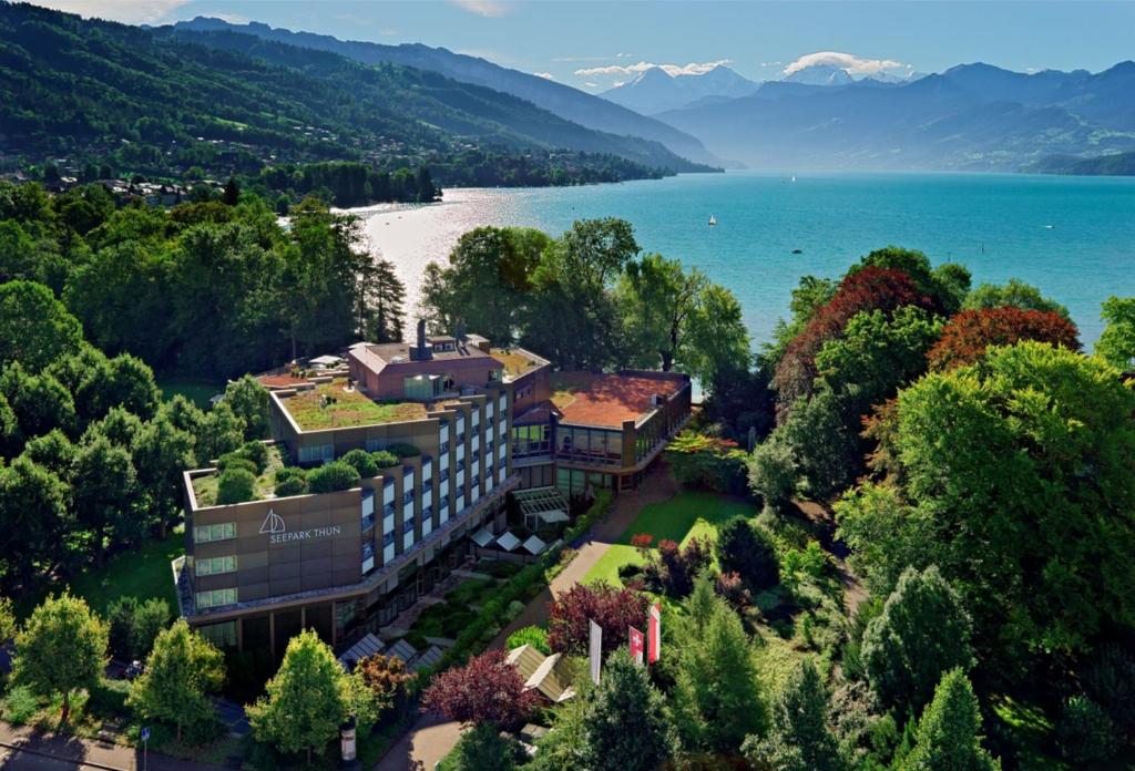 eine Luftansicht eines Gebäudes neben einem See in der Unterkunft Hotel Seepark Thun in Thun