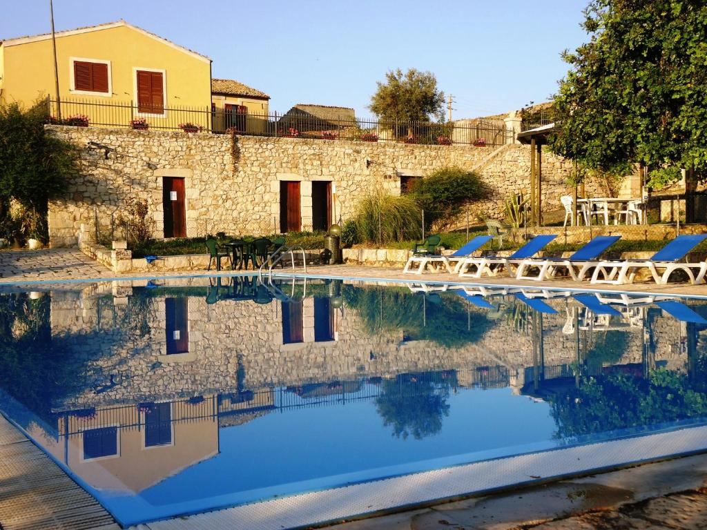 a swimming pool with lounge chairs and a building at Agriturismo Tenuta Margitello in Comiso