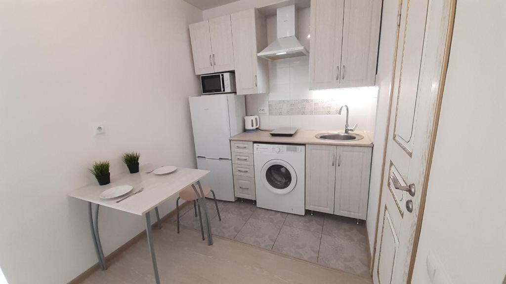 a small kitchen with a table and a washing machine at Two Apartments on Berezovy 13 in Pyatigorsk