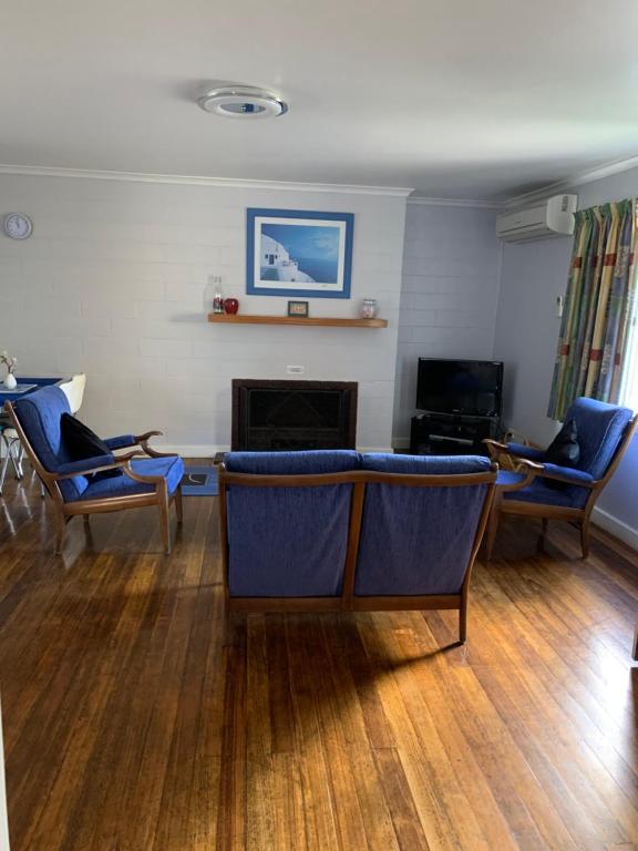 een woonkamer met blauwe stoelen en een open haard bij Orford Prosser Holiday Units in Orford