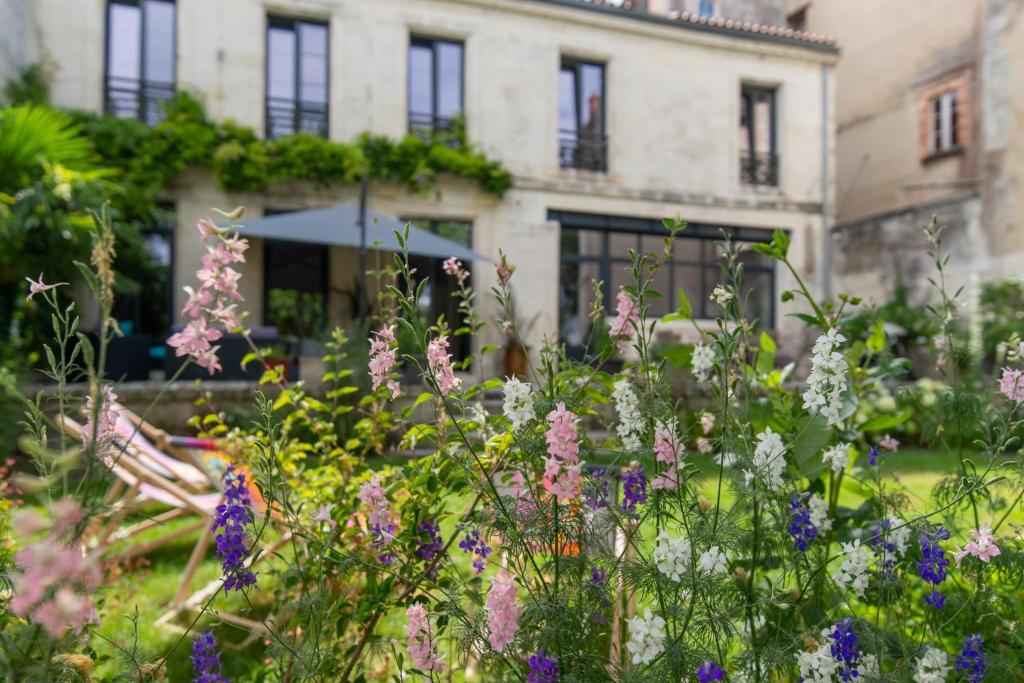 um jardim com flores em frente a um edifício em Escale Rochelaise B&B, SPA bain nordique et sauna tonneau em La Rochelle
