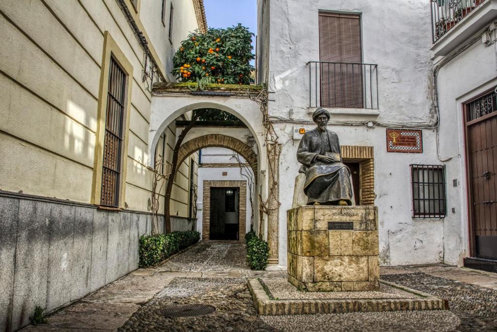 Eine Statue einer Frau, die auf einem Brunnen vor einem Gebäude sitzt. in der Unterkunft Casa Tiberíades in Córdoba