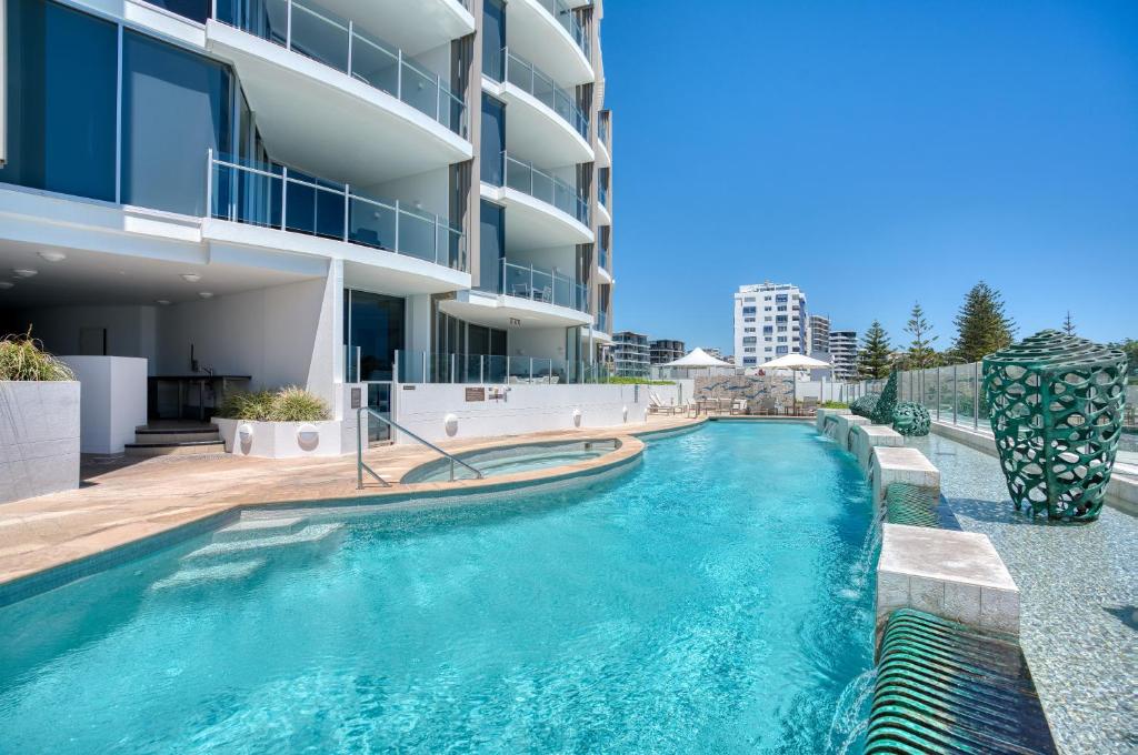 a swimming pool in front of a building at Oceans Mooloolaba in Mooloolaba