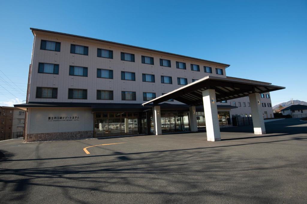 a large building with awning next to a parking lot at Fujikawaguchiko Resort Hotel in Fujikawaguchiko