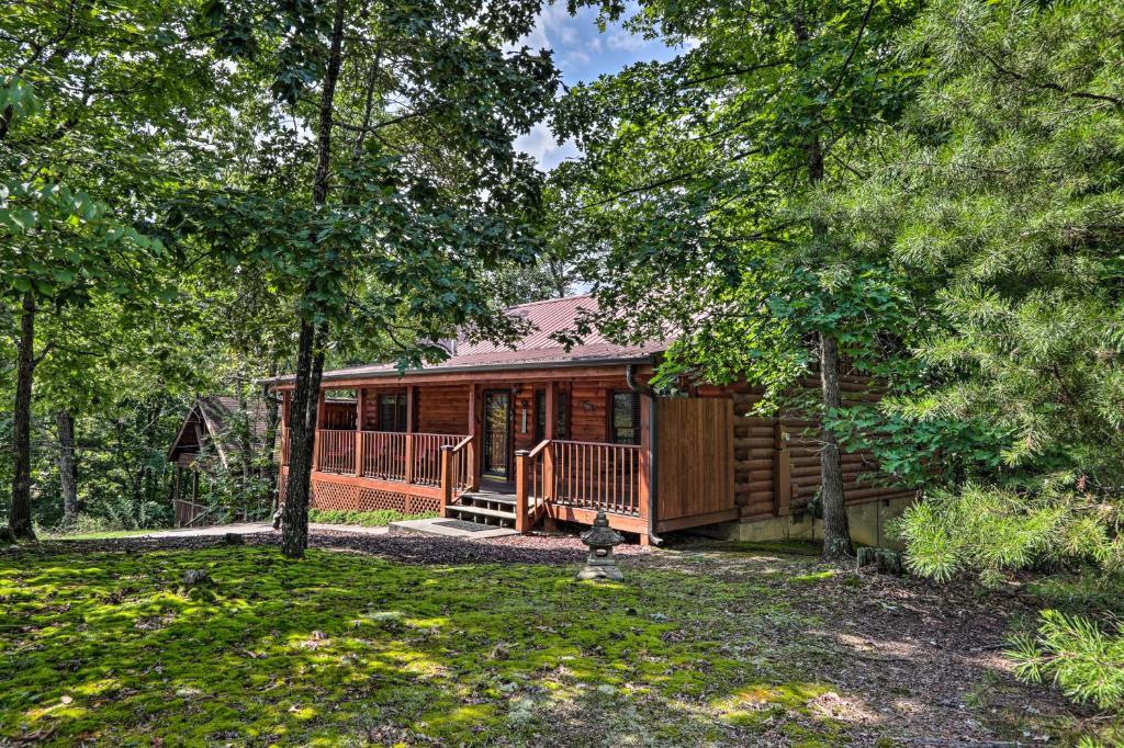een hut in het bos met een veranda en bomen bij Cabin with Deck and Fireplace Less Than 3 Mi to Dollywood! in Pigeon Forge