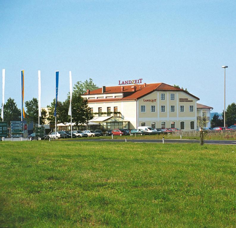 a large building with a grass field in front of it at Landzeit Motor-Hotel St. Valentin in Sankt Valentin