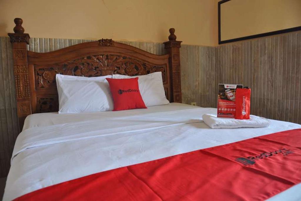 una cama con cabecero de madera y un libro sobre ella en RedDoorz near Lokawisata Baturaden, en Purwokerto