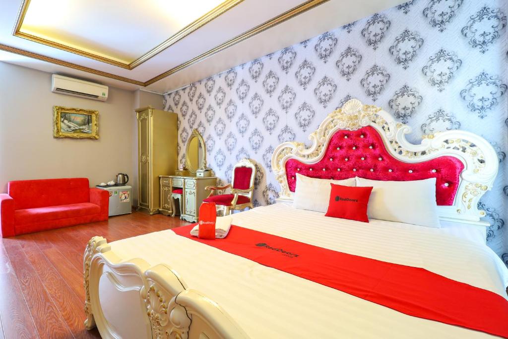 a bedroom with a large bed and a red chair at RedDoorz Bui Vien Walking Street in Ho Chi Minh City