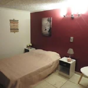 um quarto com uma cama e uma parede vermelha em Café de l'univers em Arpaillargues-et-Aureillac