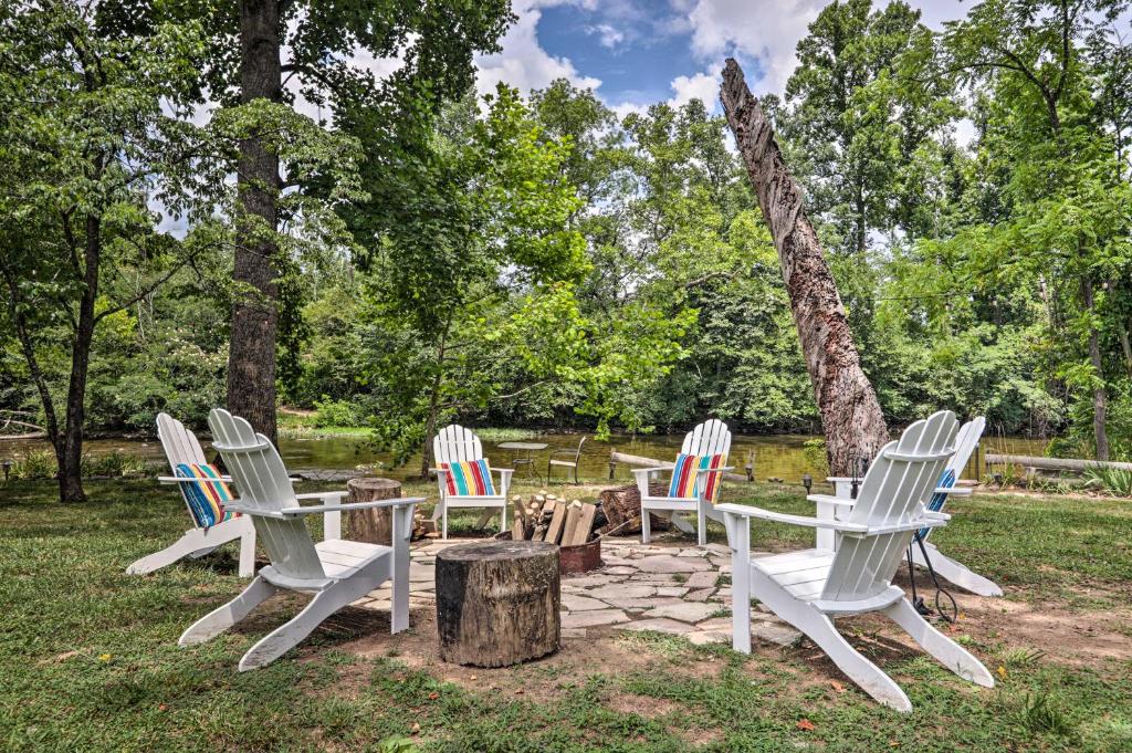 a group of white chairs around a table and a tree stump at Outdoorsmens Paradise on River with Fire Pit! in Townsend