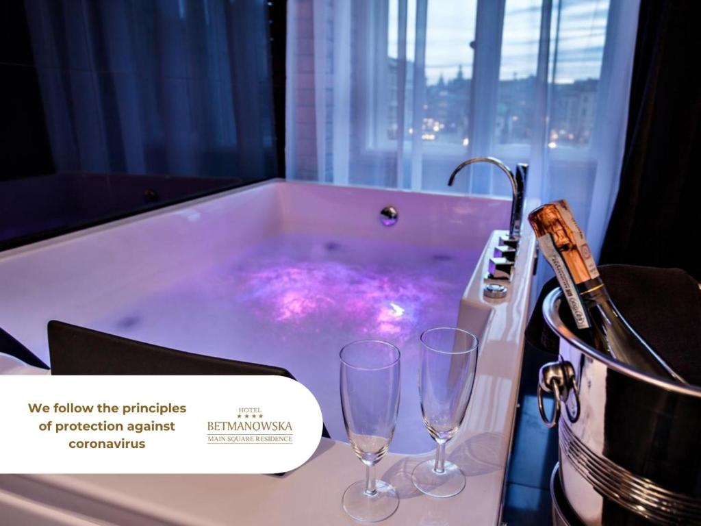 a bath tub with two wine glasses in it at Hotel Betmanowska Main Square Residence Adults Only in Kraków