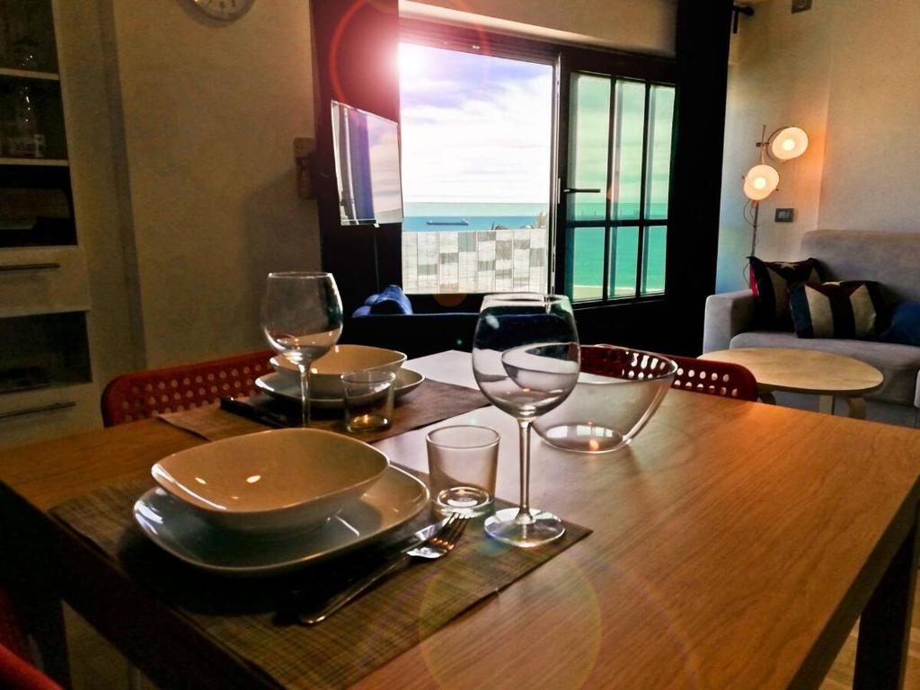 a table with wine glasses and a plate on it at MODERN & BRIGHT flat - 2 MIN from the SEA in Savona