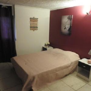 sypialnia z łóżkiem i czerwoną ścianą w obiekcie Café de l'univers w mieście Arpaillargues-et-Aureillac