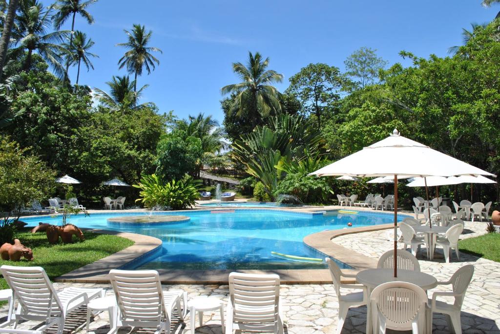 a pool at a resort with chairs and an umbrella at Hotel 7 Colinas in Olinda