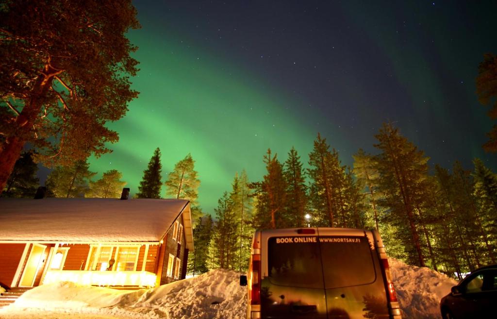 ein Bus, der vor einem Haus unter einem grünen Himmel parkt in der Unterkunft Riekko Chalet in Rovaniemi