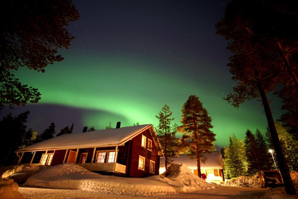 eine Hütte mit der Aurora am Himmel in der Nacht in der Unterkunft Tilhi Chalet in Rovaniemi