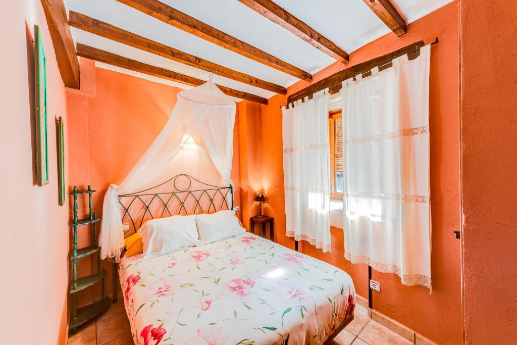 a bedroom with an orange room with a bed and a window at Casa Manadero in Robledillo de Gata