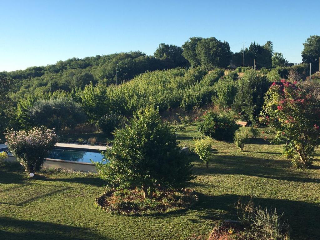 uma vista para um jardim com árvores e um lago em Aux Coteaux d'Aussac em L Honor De Cos
