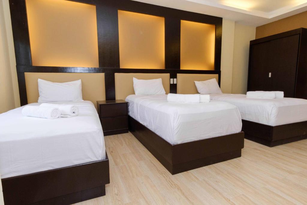 two beds in a hotel room with white sheets at Northpointe Residences in Manila