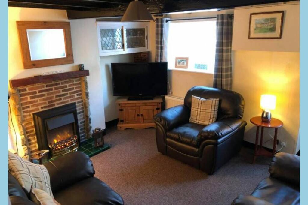a living room with a couch and a fireplace at Mena Cottage, Cosy Country and Quaint. in Hunmanby