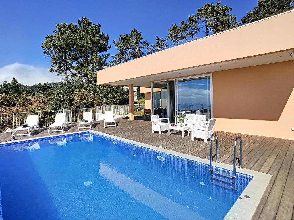 une piscine avec des chaises blanches et une maison dans l'établissement Casa Luz by LovelyStay, à Prazeres