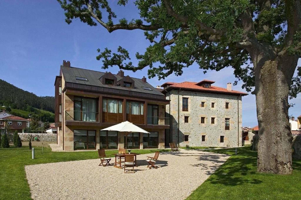 een groot huis met een tafel en stoelen ervoor bij Posada La Robla in La Cueva