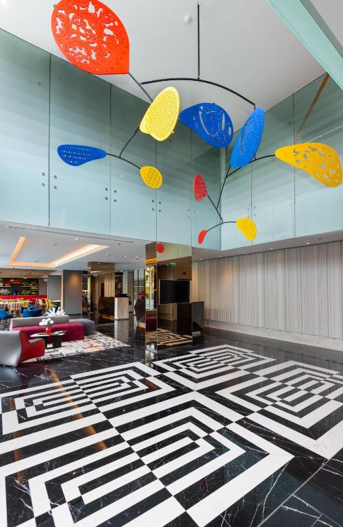 A dramatic lobby with a geometric marble floor and colorful hanging decorations.