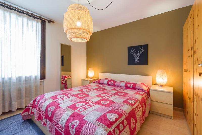 um quarto com uma cama com um cobertor vermelho e branco em SPINALE casa in centro, arrivi con gli sci! SANIFICAZIONE A VAPORE em Madonna di Campiglio