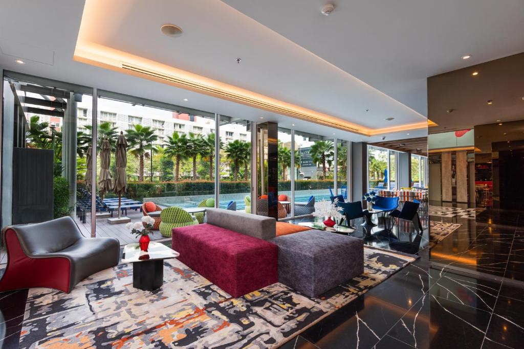 A colorful hotel lobby lounge with sofas, armchairs and floor-to-ceiling windows.