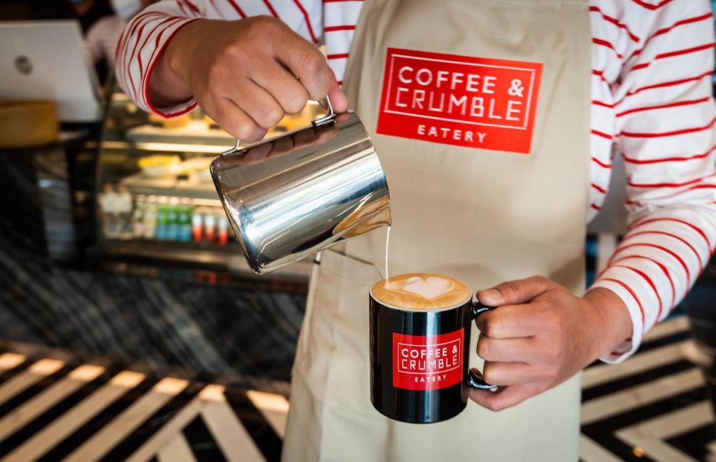 A barista pours coffee into a branded cup at the hotel café.