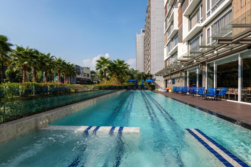 A long outdoor lap pool running beside the hotel building and landscaped grounds.