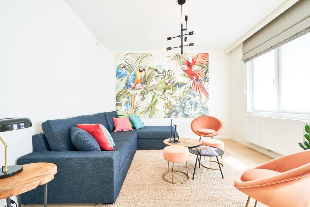 sala de estar con sofá azul y sillas en Diamant 2BR en Bruselas