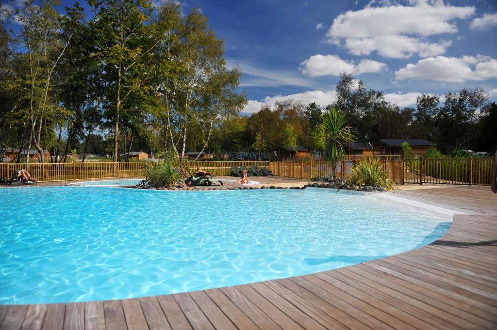 une grande piscine bleue avec une terrasse en bois dans l'établissement Mobil Home XXL2 4 chambres - Camping Bordeaux Lac, à Bruges