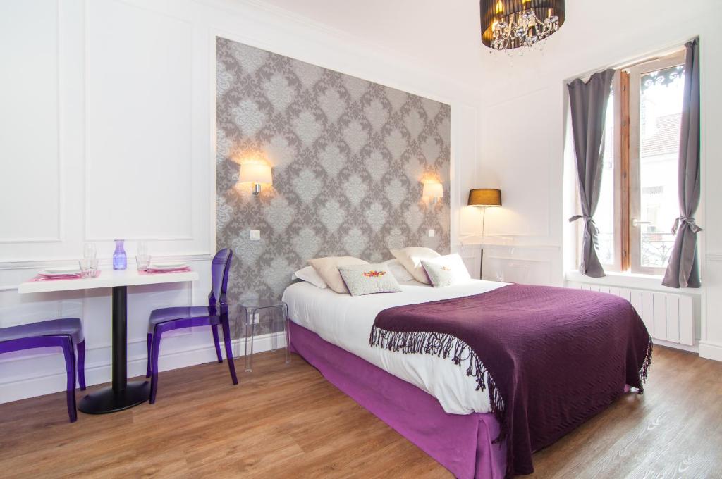 - une chambre avec un lit et une table avec des chaises violettes dans l'établissement Les Charmettes - Lyon 6ième, à Lyon