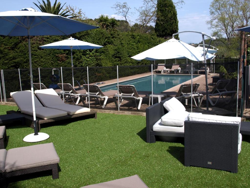 eine Gruppe von Stühlen und Sonnenschirmen neben einem Pool in der Unterkunft Hotel Cayrons Vence & St Paul de Vence in Vence