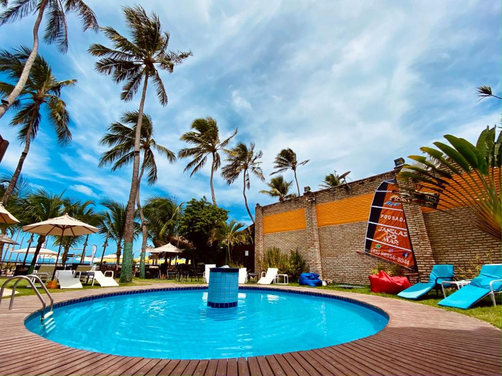 uma piscina no resort com palmeiras ao fundo em Pousada Janelas do Mar em Flecheiras