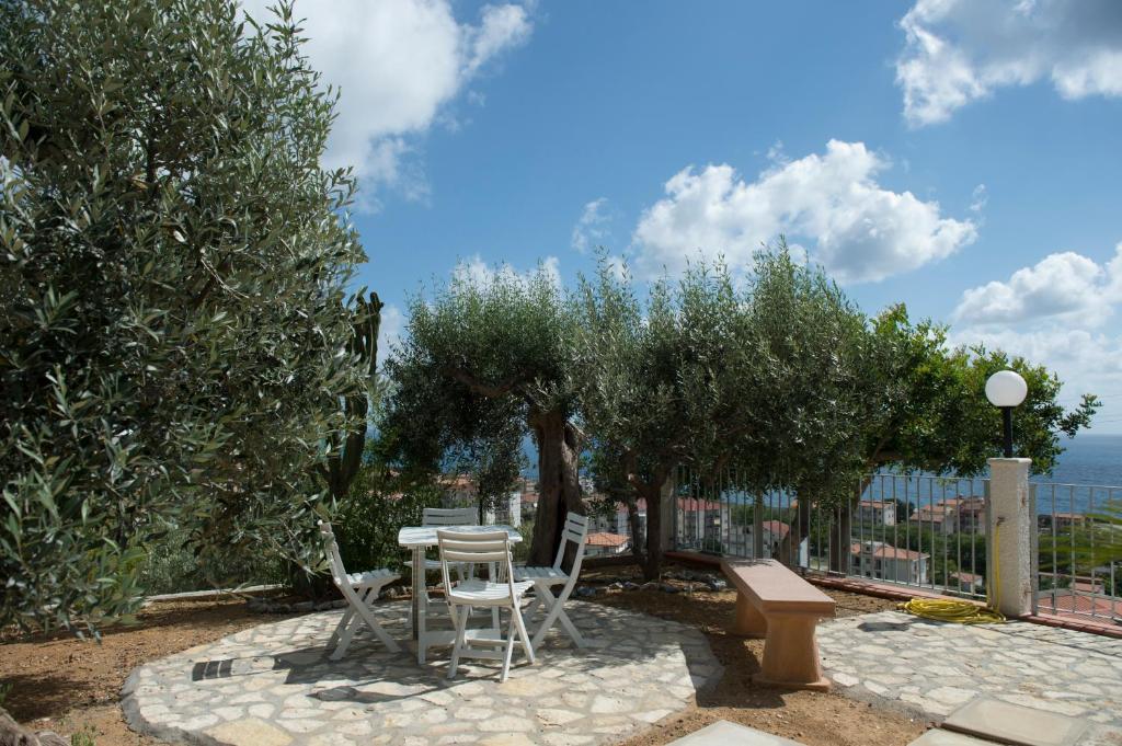 un patio con mesa, sillas y árboles en L'Ulivo Sul Mare, en Cetraro
