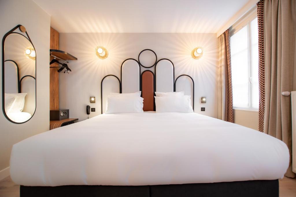 ein großes weißes Bett mit weißen Kissen im Schlafzimmer in der Unterkunft Hotel de L'Esperance in Paris