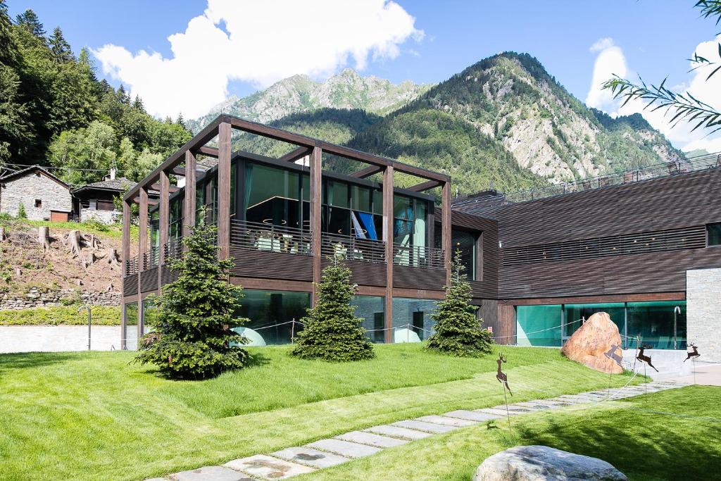 una casa grande con montañas en el fondo en Mirtillo Rosso Family Hotel, en Alagna Valsesia