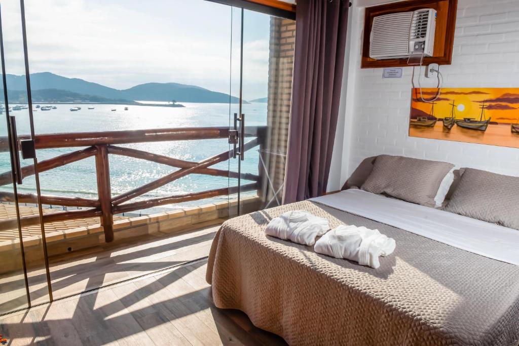 a bedroom with a bed and a view of the ocean at Cantinho dos Anjos Suítes in Arraial do Cabo
