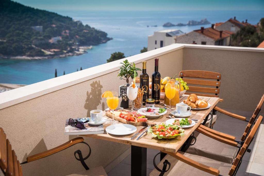 uma mesa com comida e garrafas de vinho numa varanda em Luxury Apartment Edi em Dubrovnik