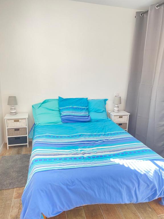 a blue bed with blue pillows in a bedroom at Le sable chaud in Saint-Pierre-dʼOléron