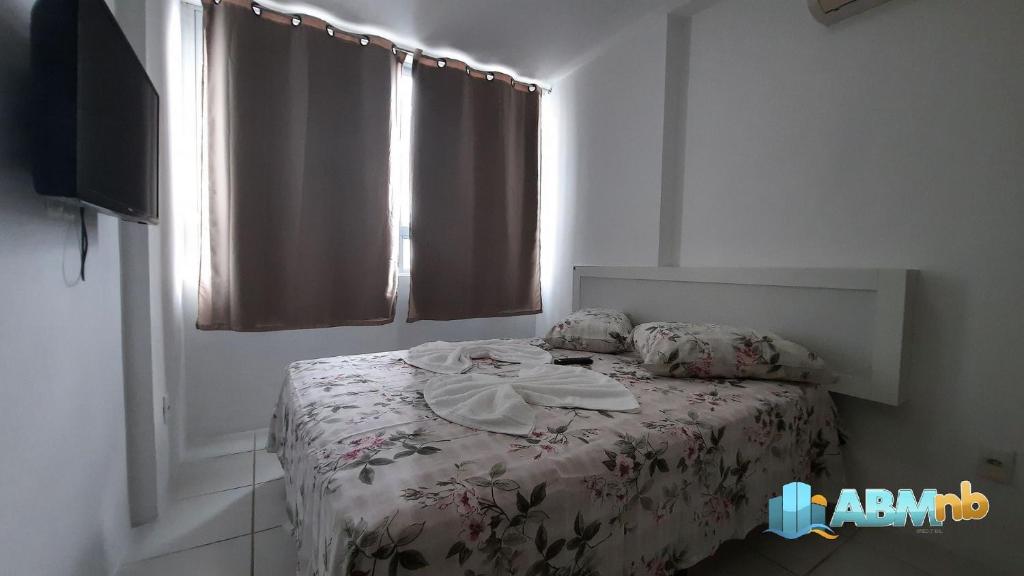- une chambre avec un lit doté d'une couverture fleurie et d'une fenêtre dans l'établissement Apto. 1 dormitório no Edifício Manhattan home service 605, à Caruaru