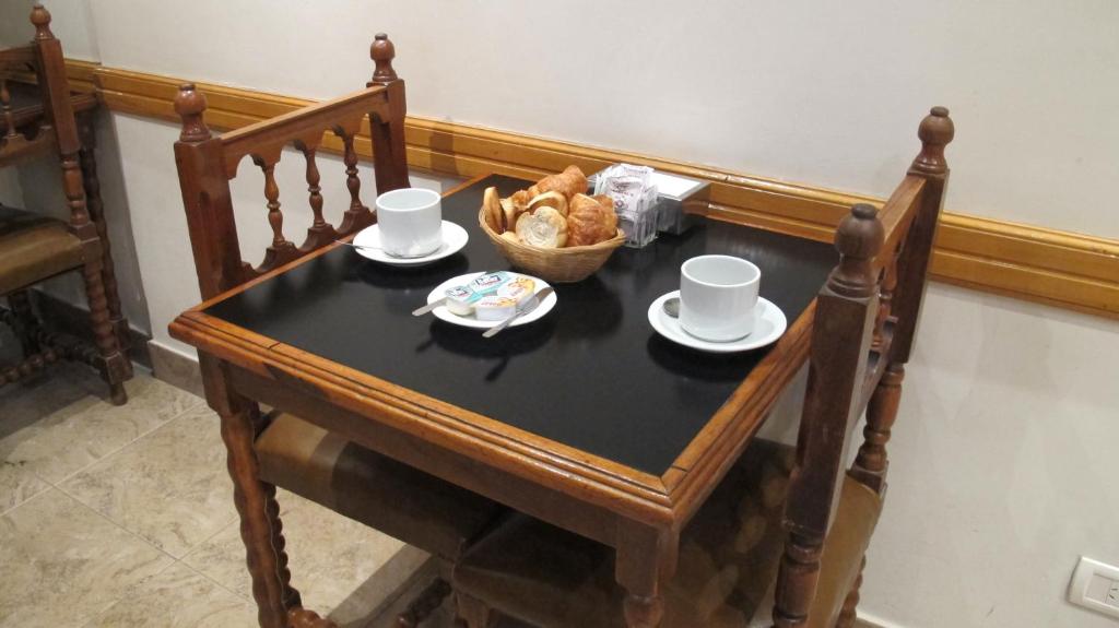 una mesa con tazas y una cesta de pan. en Gran Hotel Libertad en Buenos Aires