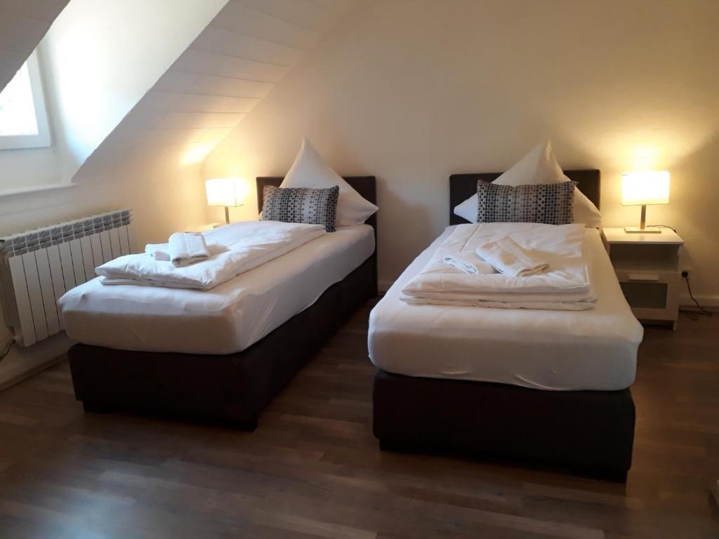 twee bedden in een kleine kamer met twee lampen bij Ferienwohnungen Haus Scheidter 42 in Saarbrücken